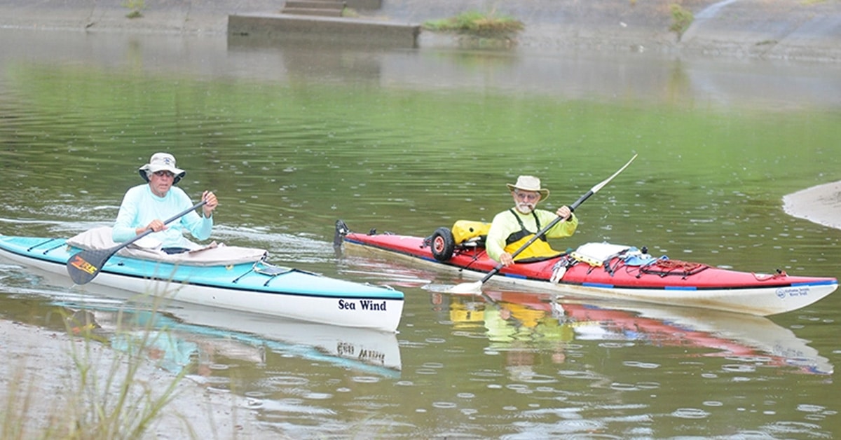 Two Men Paddling Down A River