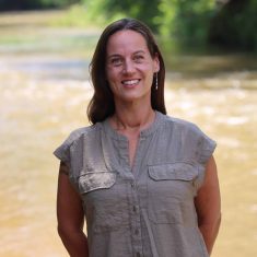 A Woman Standing Next To A Body Of Water