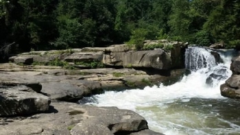 a large waterfall next to a rock