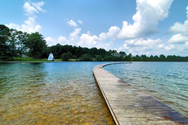 A Wooden Boardwalk Stretching Into A Lake