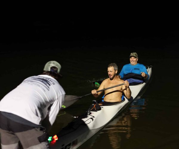 Tandem Kayakers Pulling Their Boat Over At Night