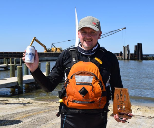 A Man Holding His Great Alabama 650 Trophy Near The River Bank