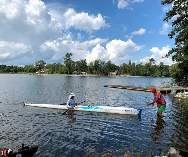 A Group Of People Rowing A Boat In A Body Of Water