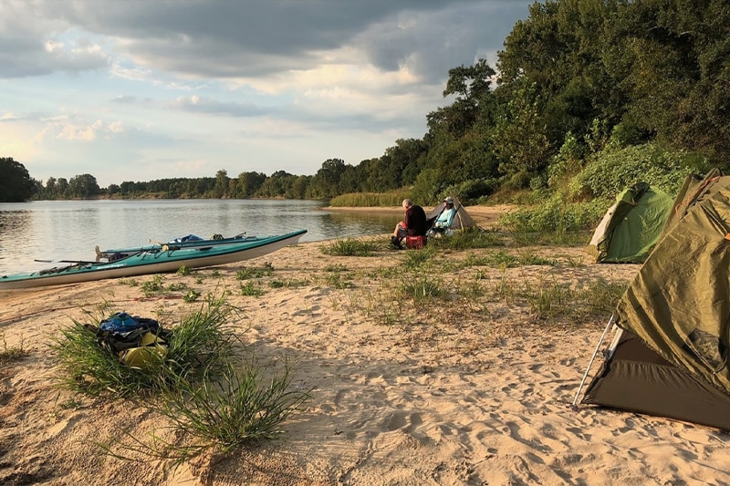 Kayakers camping on the shore of a river