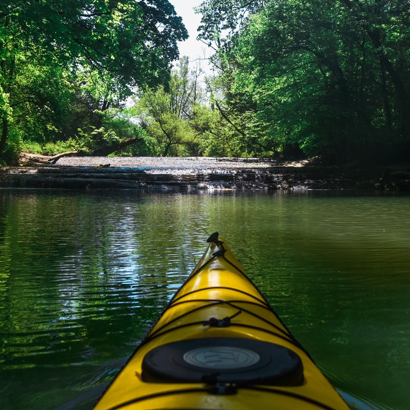 Sitting in a kayak near a small cascading waterfall