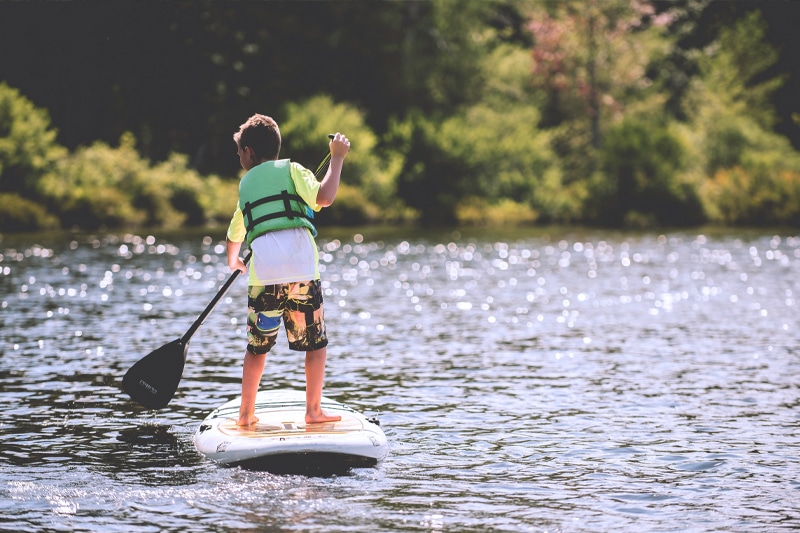 A kid paddleboarding down a river