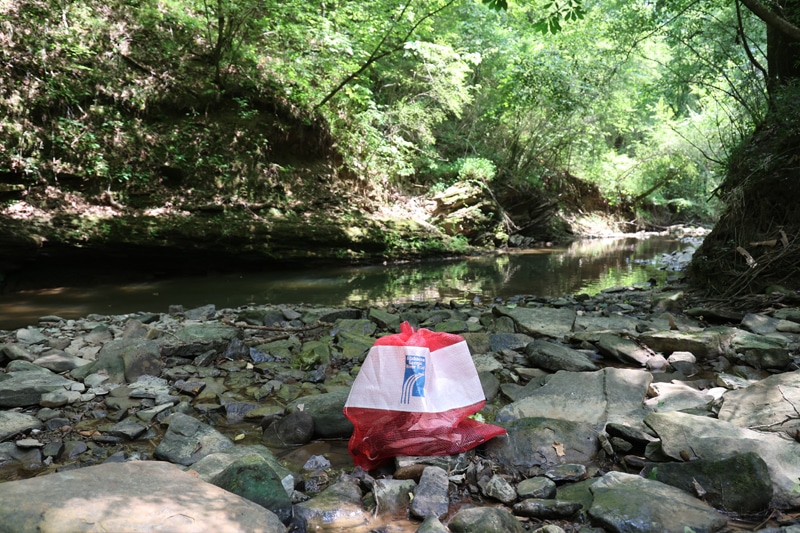 A drybag resting on rocks near a creek