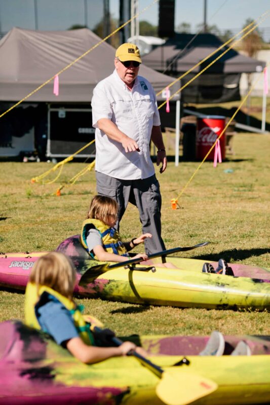 A man helping kids get ready in their kayaks