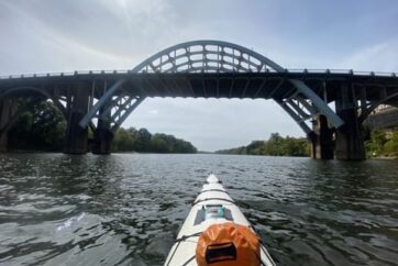 Kayaker approaching a bridge