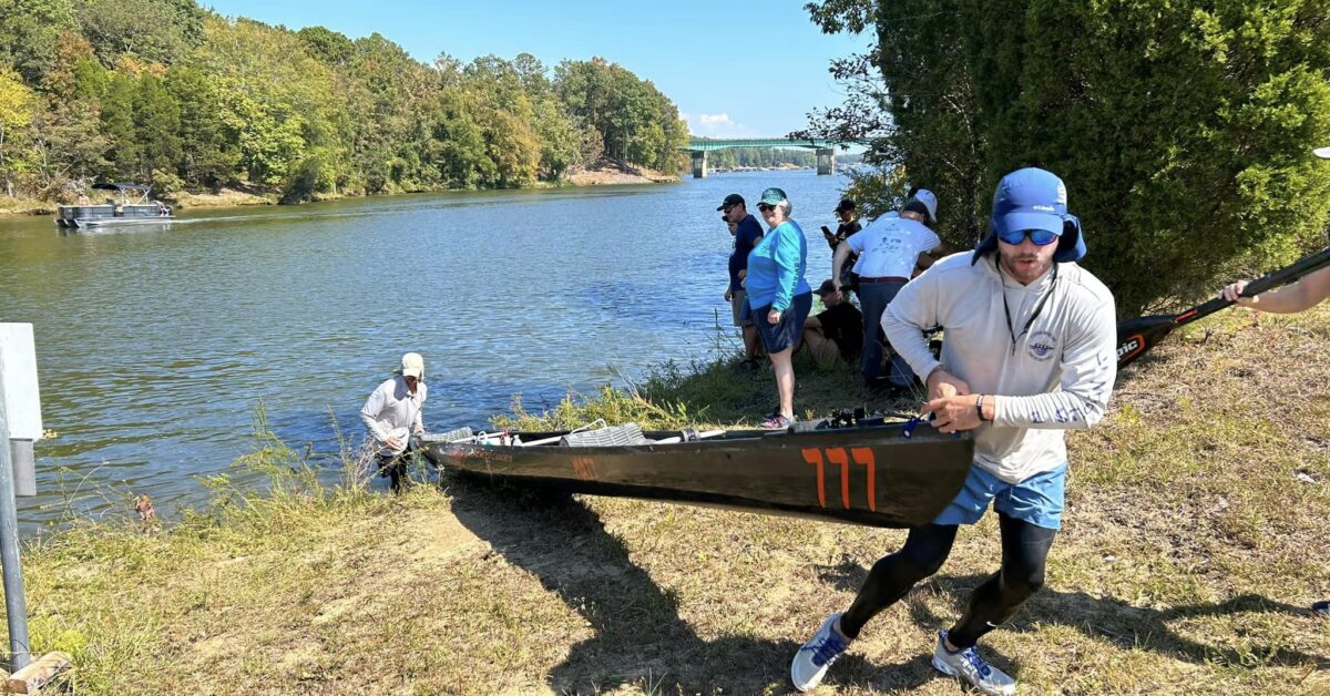 Two People Pulling A Kayak Out Of A River