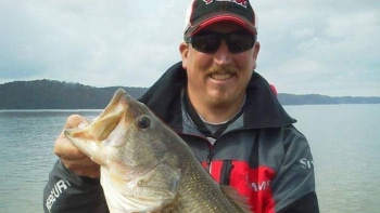 a man holding a fish in front of a body of water