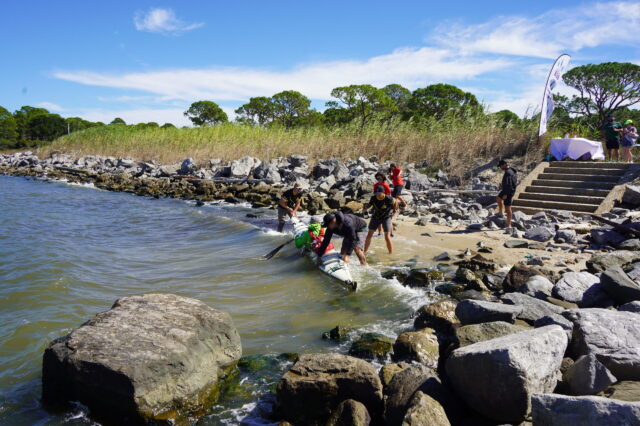 Men Loading A Kayak Into A Body Of Water