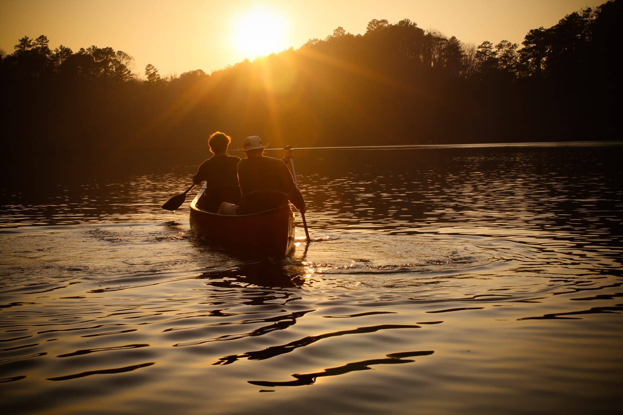 a small boat in a body of water with a sunset in the background